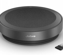 Pyöreä, tummanharmaa Jabra-kaiutin mustalla ritiläetupaneelilla, mukana pieni USB-sovitin, näkymä yläkulmasta.