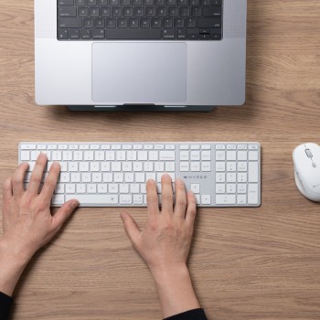 Targus Hyper Hyperspace Wireless Bluetooth Keyboard for a Modern Workspace. A person typing on a white Targus Hyper Hyperspace keyboard at a wooden desk, with a laptop in the background.